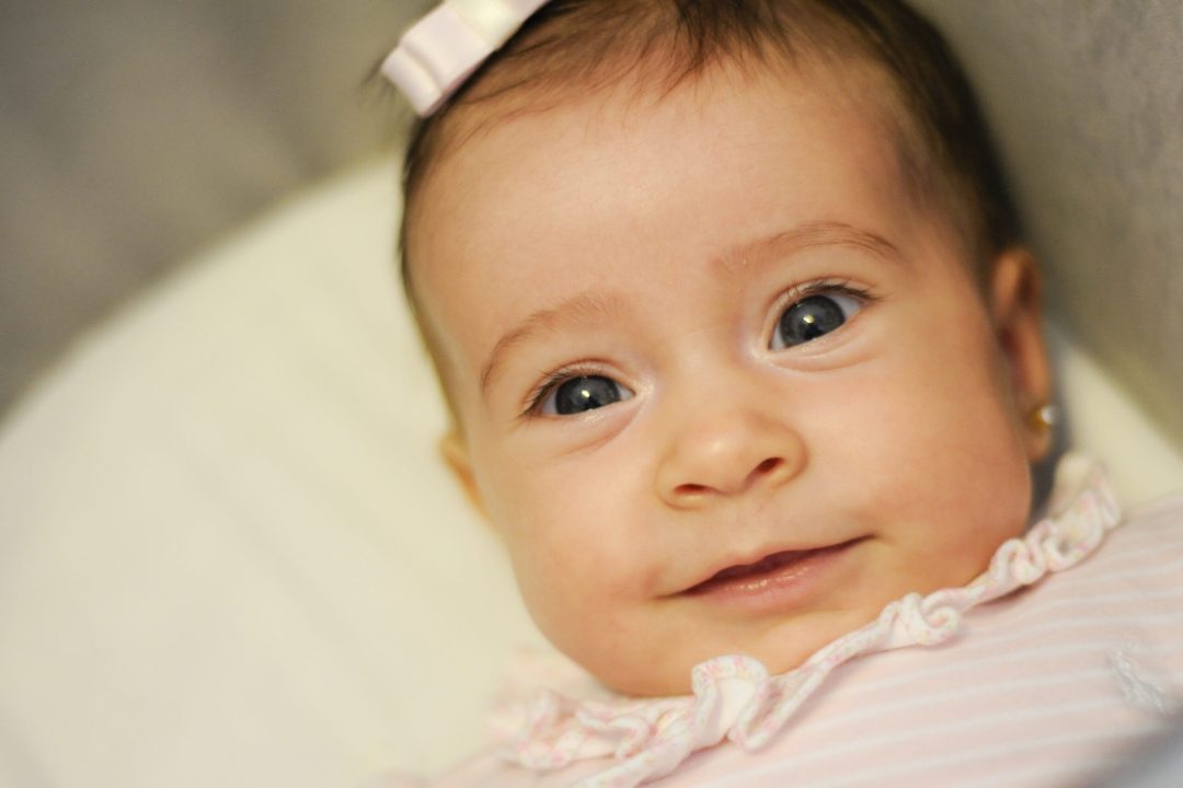 close em bebe branco, menina, com brincos, sorrindo pra a camera